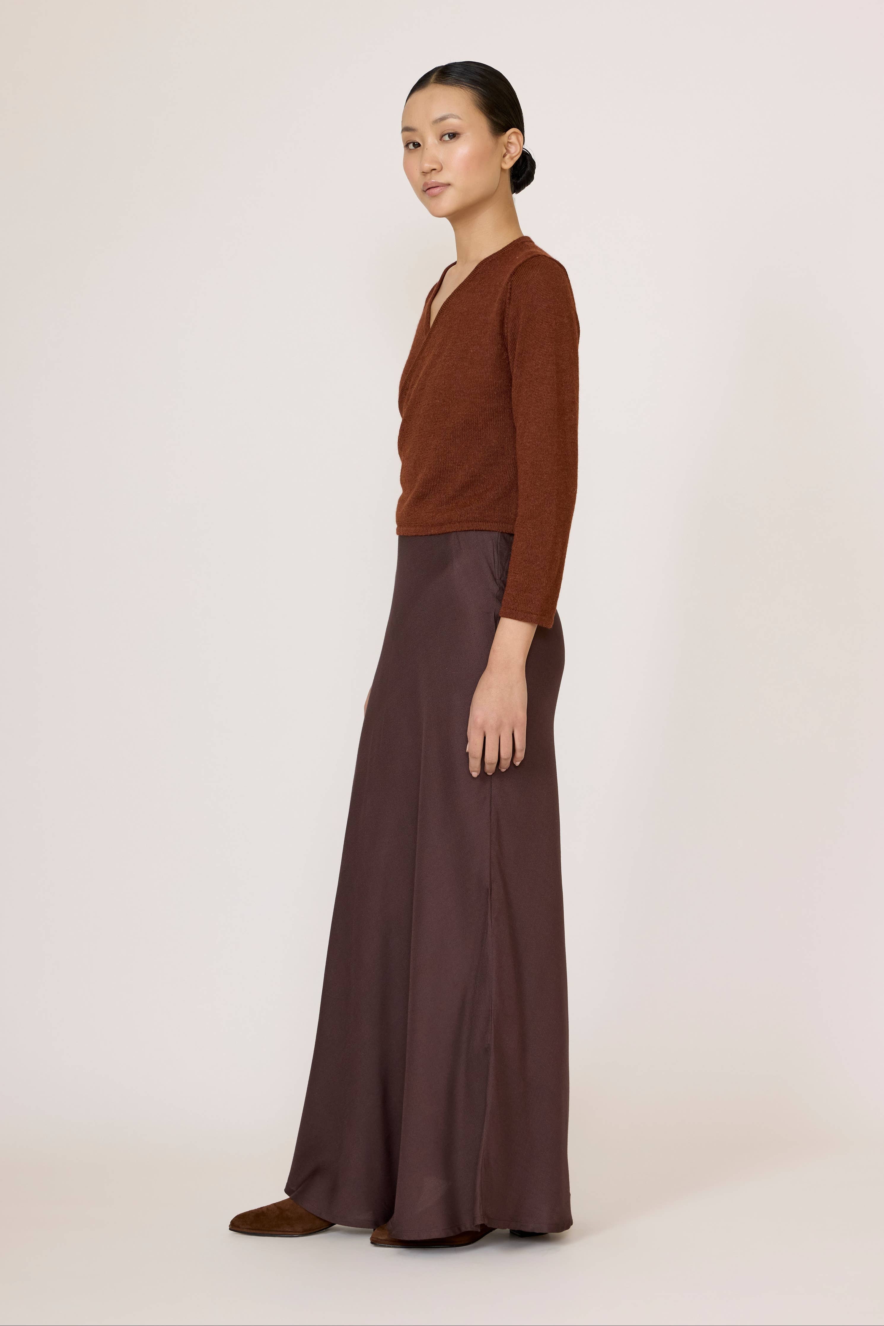 Chocolate brown bias maxi skirt by LAUDE, flowing fabric with a high waist and elegant drape, shown laid flat.