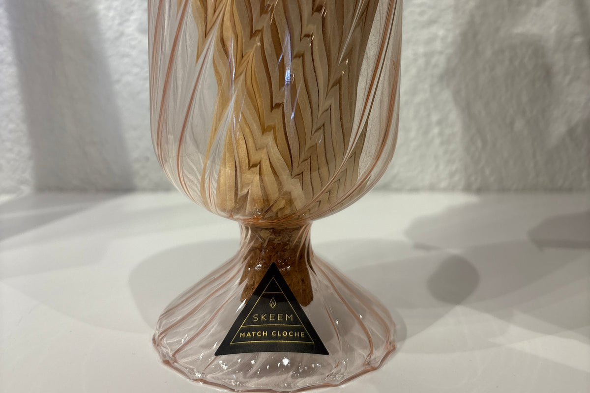 SKEEM glass match cloche covering a set of candles and matches on a wooden surface. Clear glass dome with candles inside.