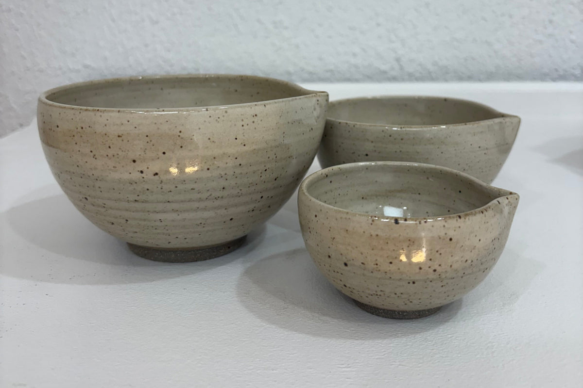 Set of handmade ceramic nesting bowls by Innovate Ceramics, showcasing smooth, glazed surfaces in various sizes for kitchen use.
