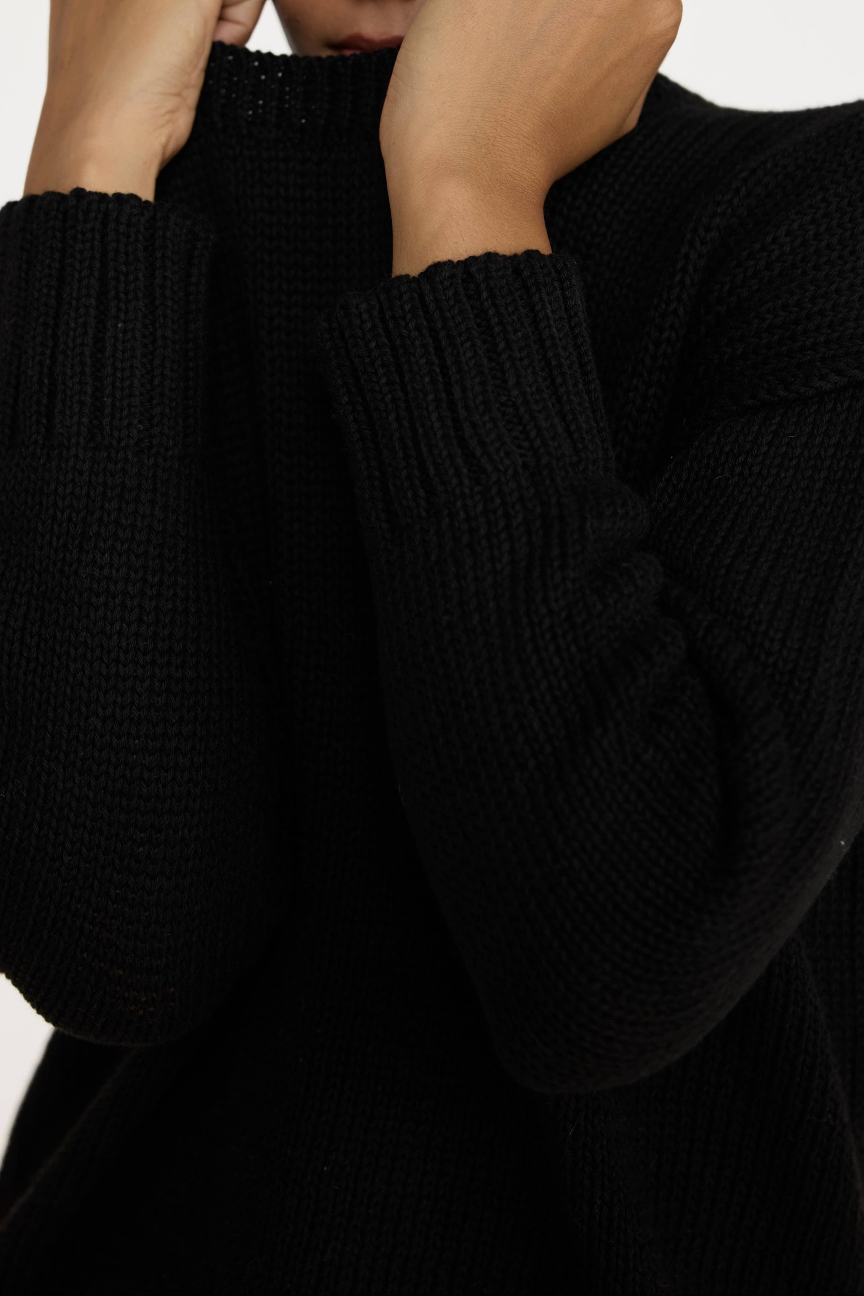 Black oversized crewneck sweater by LAUDE, featuring a relaxed fit and soft knit fabric, displayed on a neutral background.