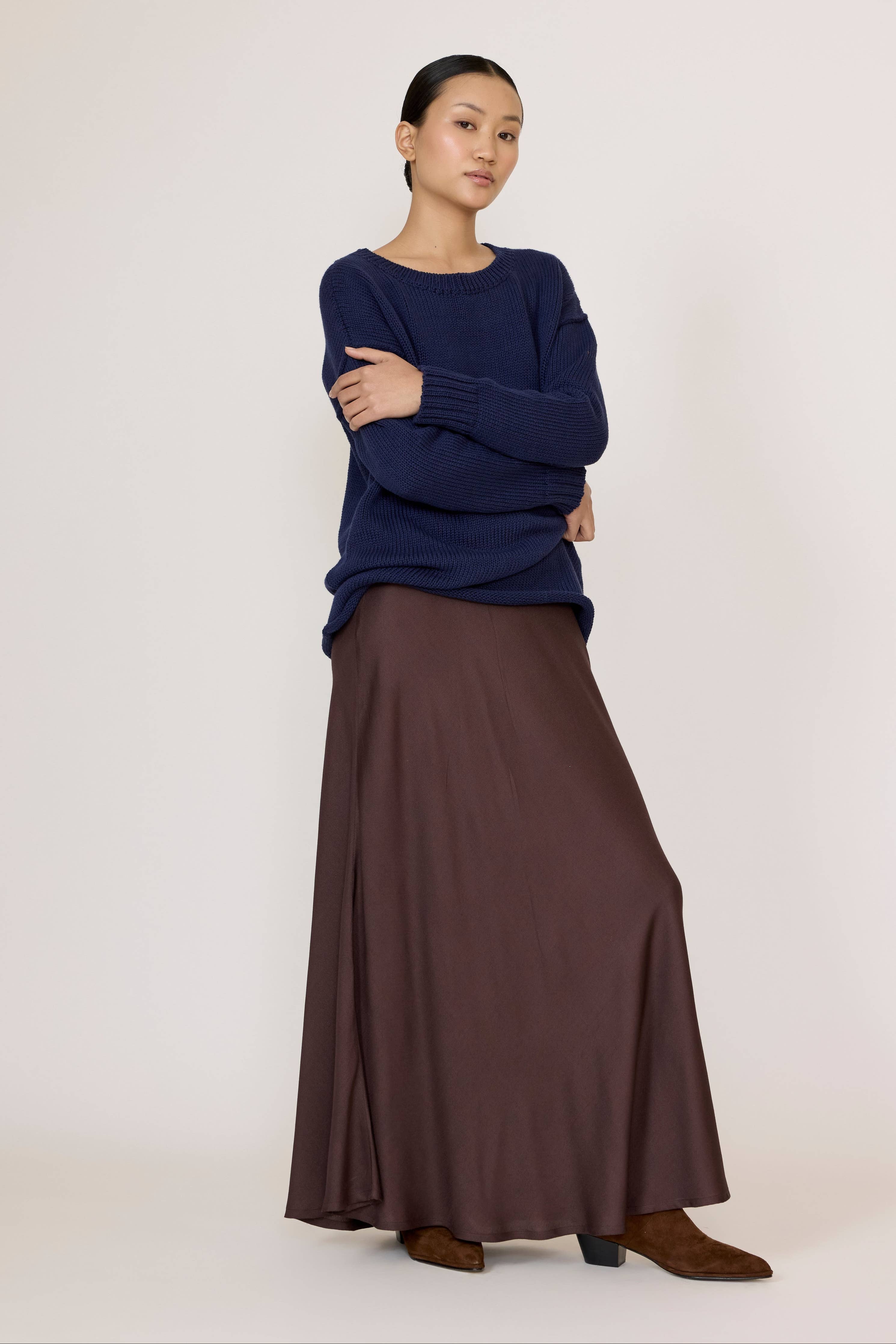 Chocolate brown LAUDE bias maxi skirt with flowing fabric and high waist, shown on a model against a neutral background.