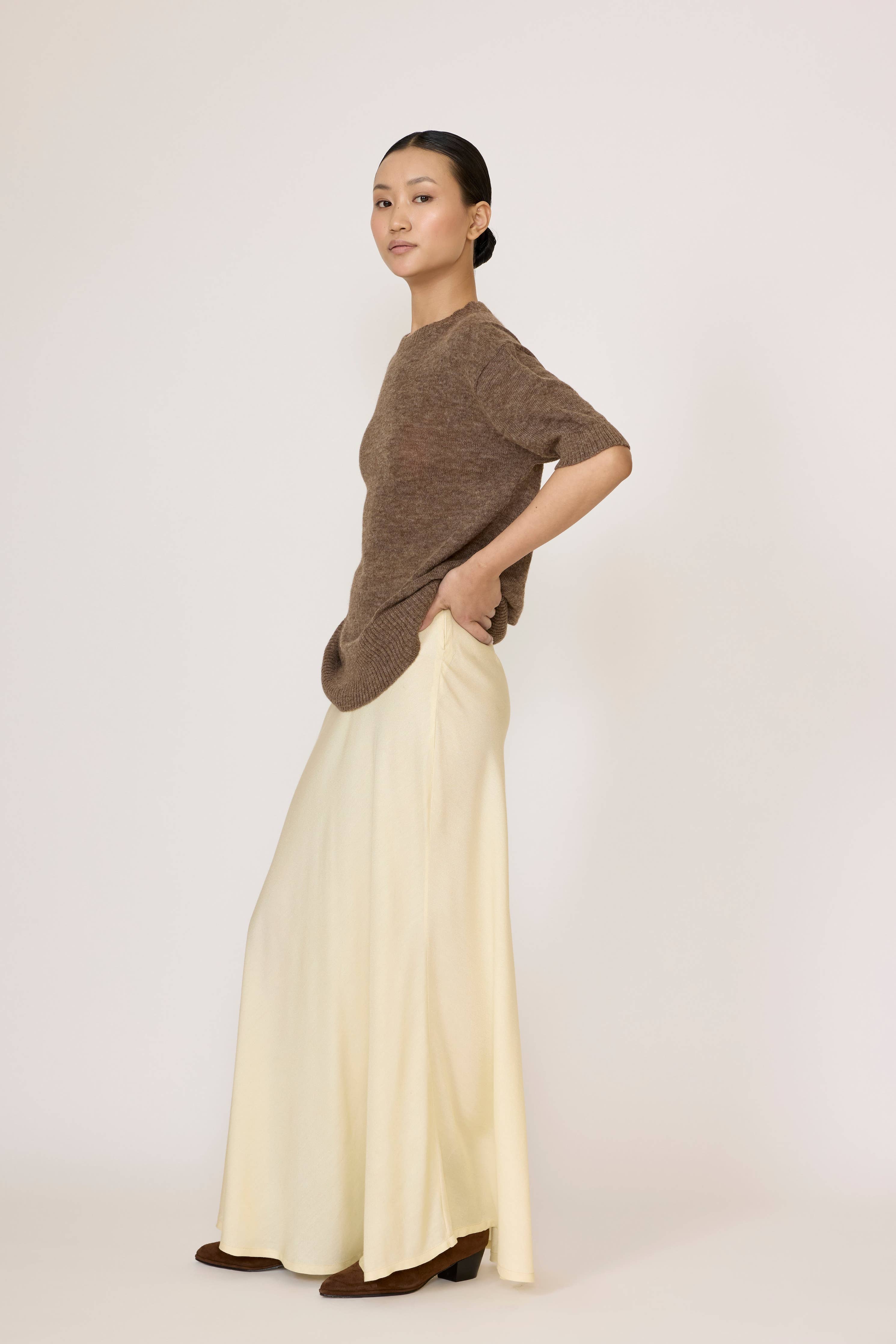 LAUDE Bias Maxi Skirt in butter yellow, flowing fabric with a high waist and subtle drape, styled for a casual elegant look.