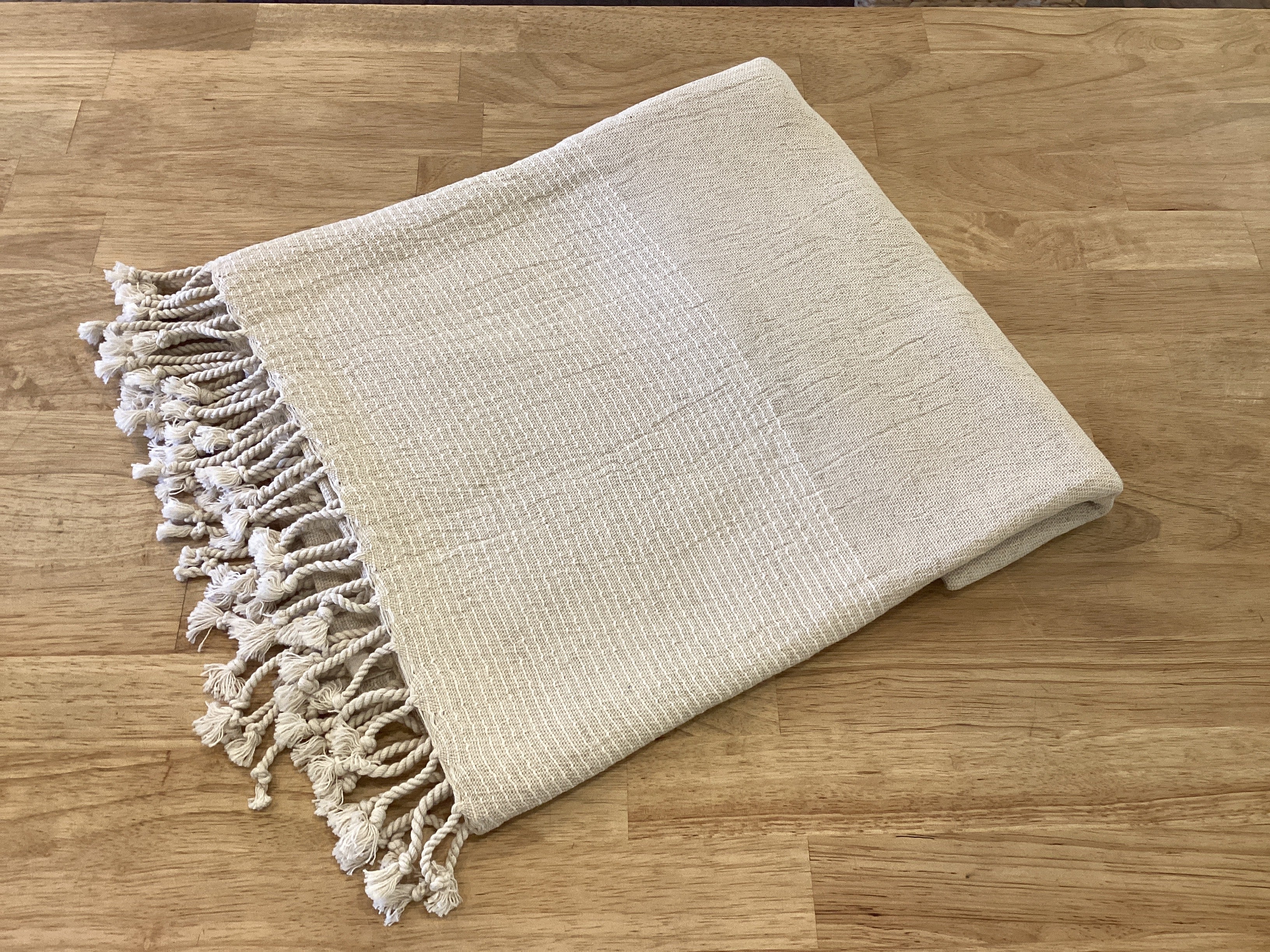 Lavender Road linen Turkish body towel draped over a wooden surface, showcasing its soft, textured fabric and natural color.