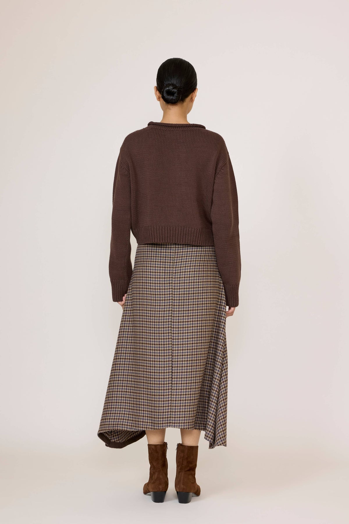 LAUDE wool plaid flowy midi skirt hanging on a rack, showcasing its soft fabric and classic plaid pattern.