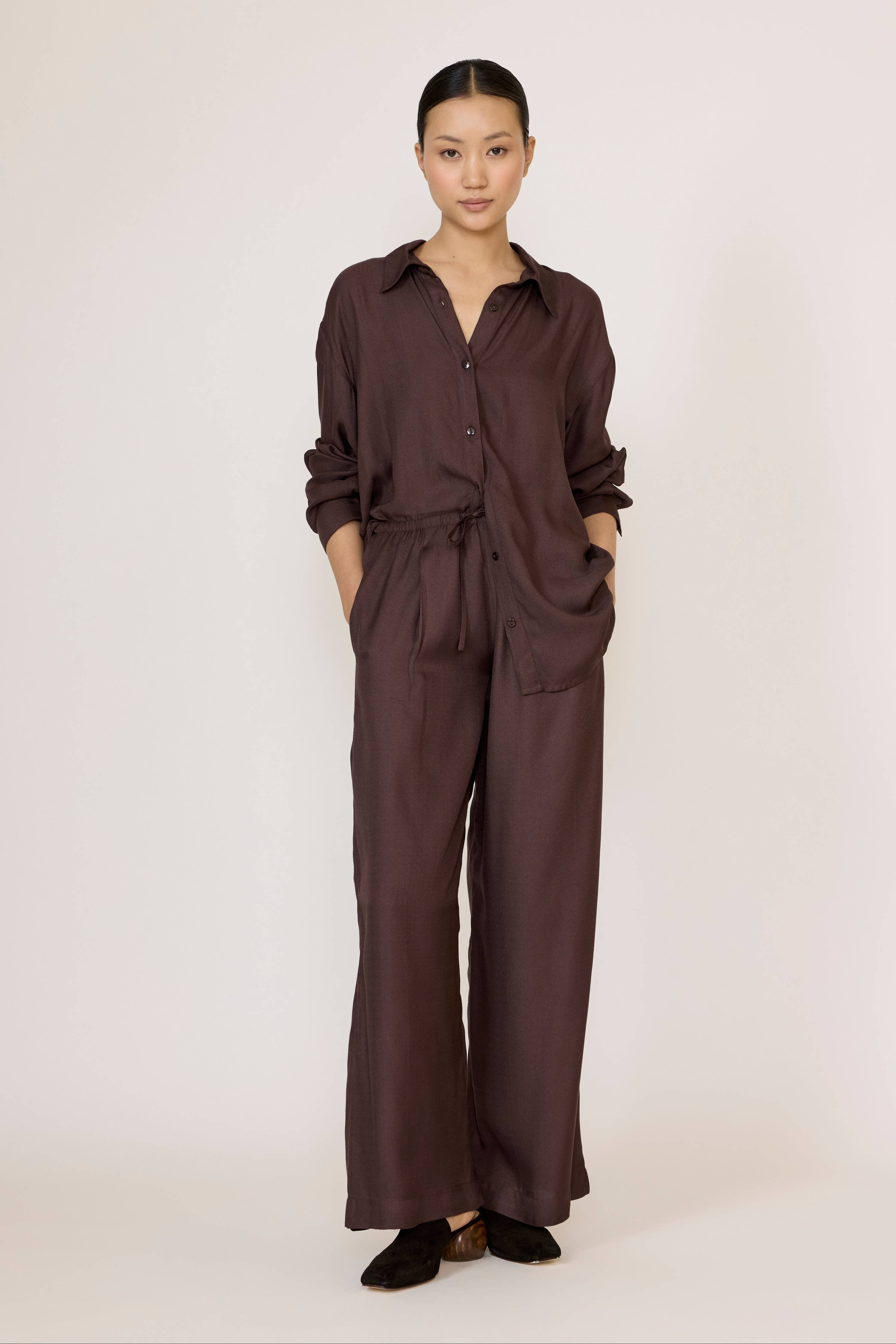 LAUDE Easy Pant in chocolate brown, featuring a relaxed fit and soft fabric, displayed on a model with a close-up of the pant's waistband.