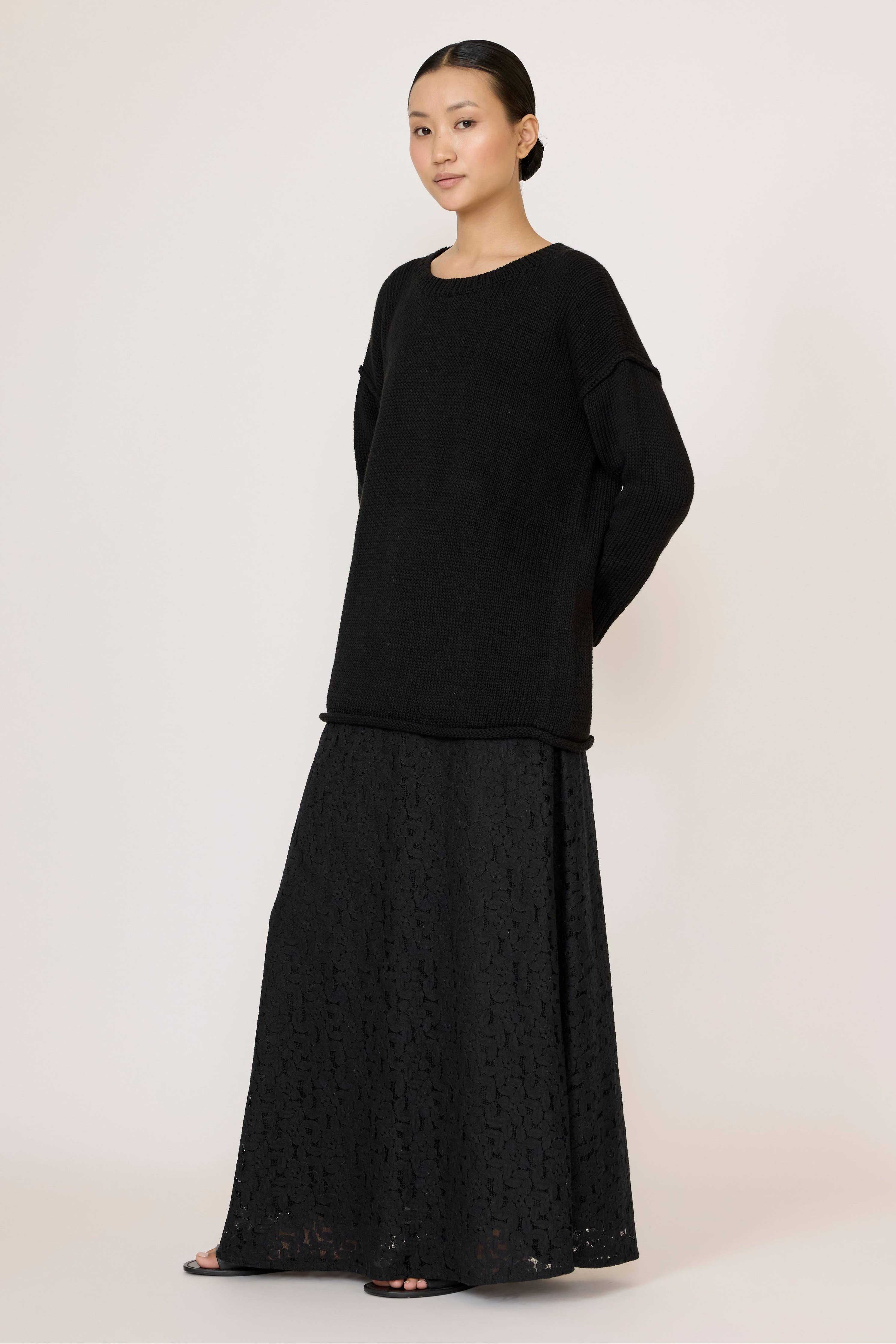 Black oversized crewneck sweater by LAUDE, shown on a model, featuring a relaxed fit and soft knit fabric.